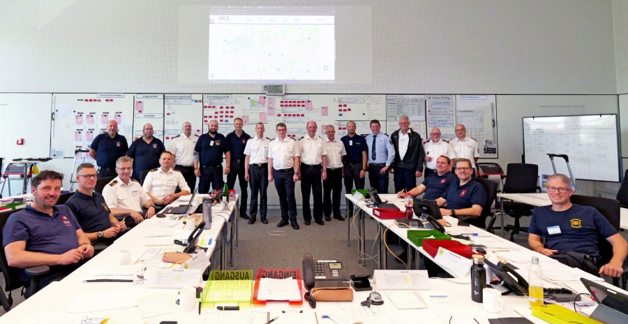 Die Teilnehmenden der Kreiseinsatzleitung beim Lehrgang am Institut der Feuerwehr (IdF) an den Arbeitsplätzen der Stabsbereiche und vor der Lagewand zusammen mit Dozent Thorsten Magdalinski (hinten r.).  © Verband der Feuerwehren im Kreis Paderborn 